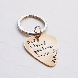 May include: Gold guitar pick keychain with the text "Dad, I loved you first. Liv 9.9.19" engraved on it.