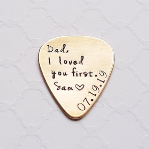 May include: Gold guitar pick with the text "Dad, I loved you first. Sam 07.19.19" engraved on it.