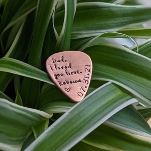 May include: A copper guitar pick with the text "Dad, I loved you first. Rebecca 07.31.21" engraved on it.