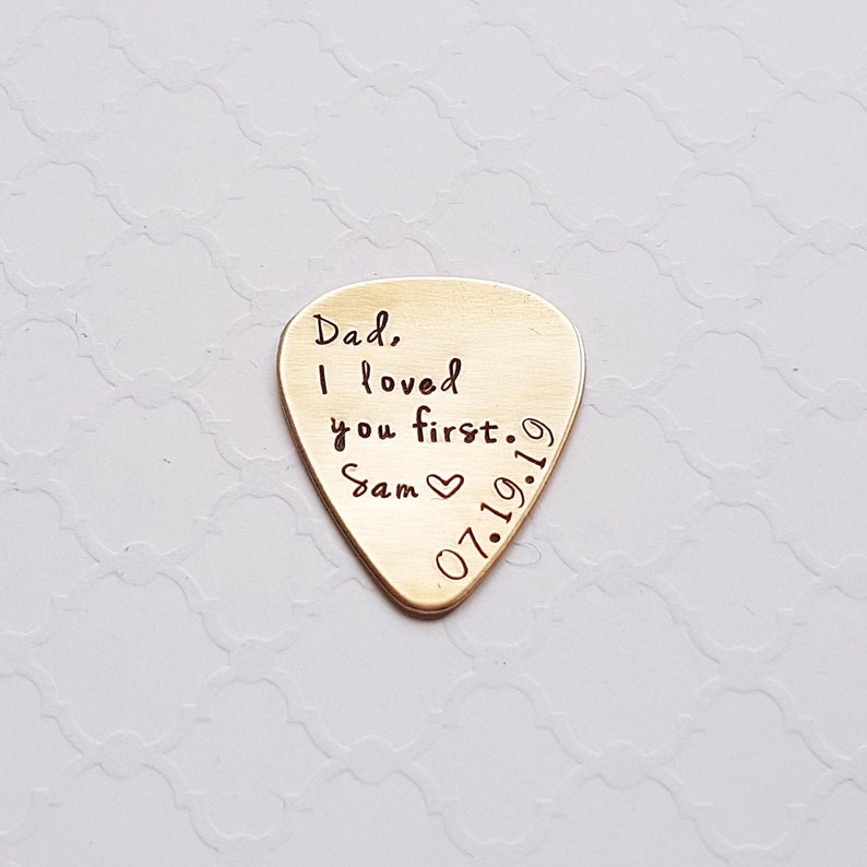 May include: Gold guitar pick with the text "Dad, I loved you first. Sam 07.19.19" engraved on it.