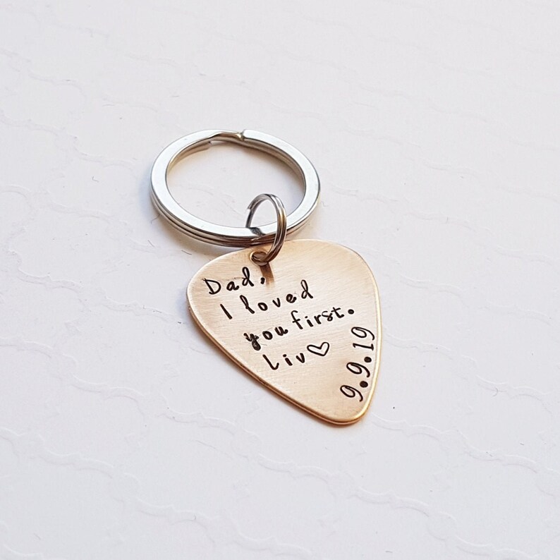 May include: Gold guitar pick keychain with the text "Dad, I loved you first. Liv 9.9.19" engraved on it.