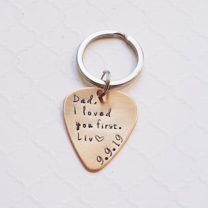 May include: Gold-colored guitar pick keychain with the text "Dad, I loved you first. Liv 9.9.19" engraved on it.