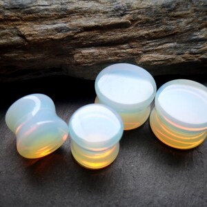 May include: Four opalite ear gauges in different sizes. The gauges are a milky white color with a slight iridescent sheen.