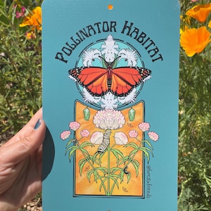 Puede incluir: Un letrero met&aacute;lico turquesa con las palabras "Pollinator Habitat" y un gr&aacute;fico de una mariposa monarca. El letrero tambi&eacute;n presenta ilustraciones de una oruga, una cris&aacute;lida y flores. El letrero est&aacute; sostenido por una persona.