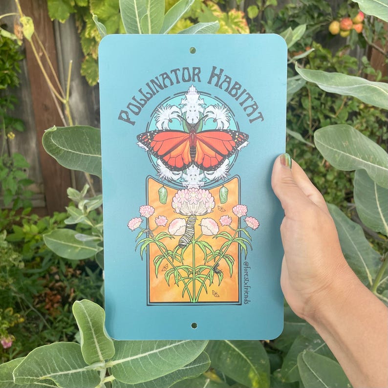 Puede incluir: Un letrero met&aacute;lico turquesa con las palabras "Pollinator Habitat" y un gr&aacute;fico de una mariposa monarca, una oruga y flores. El letrero est&aacute; sostenido por una mano sobre un fondo de follaje verde.