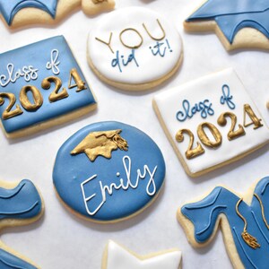 - Royal blue circle shaped cookie with "Emily" written on it in white and a gold graduation cap above it

- White circle shaped cookie with "YOU did it!" with "YOU" in gold and "did it!" in royal blue