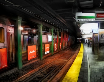May include: A yellow line runs down the center of a train platform with a train on the left and a sign that reads "B - Boston College" on the right. The platform is made of concrete and has a brick pattern.