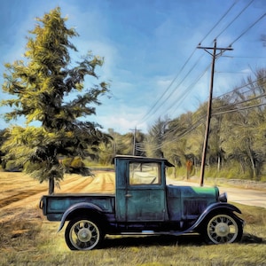 May include: An antique teal pickup truck parked on a grassy area next to a tree and a road. The truck has a black roof and white-walled tires. A power pole with wires is visible in the background, under a blue sky.