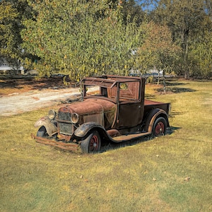 May include: A rusty, vintage pickup truck parked in a grassy field. The truck is brown and has a wooden bed. The truck is surrounded by trees.