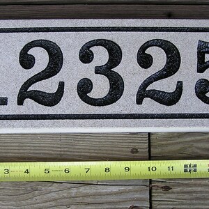 May include: A white rectangular stone house number plaque with black numbers "12325" in a decorative font.