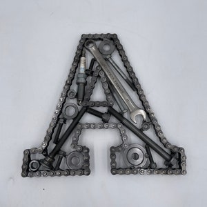 May include: A metal letter A made from a chain, bolts, nuts, washers, and a wrench. The wrench is labeled "Chrome Vanadium".