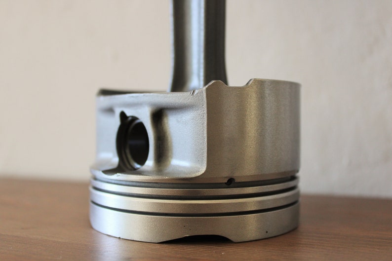 Close-up view of the base of a clock made out of a car engine's piston, finished in gunmetal gray.