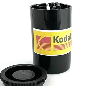 May include: A black plastic container with a yellow and red label that says "Kodak Film".