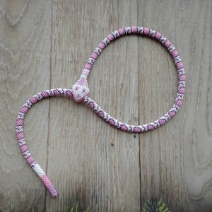 Può includere: Una collana di serpente in perline rosa e bianche con una testa di serpente in perline.
