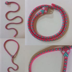 May include: A pink and green beaded snake necklace with a flower design. The necklace is shown in three different positions, including a coiled snake, a straight snake, and a snake with its head raised.