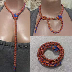 Può includere: Una lunga collana di perline con un design a forma di serpente. La collana è realizzata con perline arancioni, blu e argentate. La collana è mostrata in tre posizioni diverse: indossata intorno al collo, annodata e distesa.