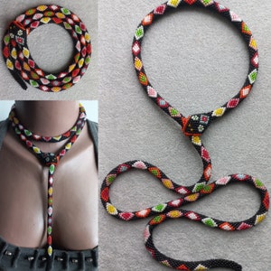 May include: A multi-strand beaded necklace with a black base and colorful geometric patterns. The necklace is made of small beads and has a long, dangling pendant.