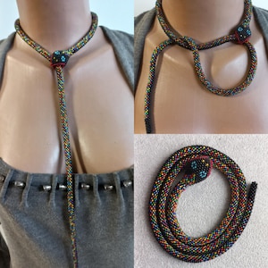 Peut inclure: Un collier de serpent en perles avec une finition colorée et irisée. Le serpent est enroulé et a une perle noire pour l'œil. Le collier est assez long pour être porté comme un collier ras du cou ou un collier long.