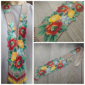 May include: A long beaded necklace with a floral design featuring red, yellow, and green beads. The necklace is made of small beads and has a fringe at the bottom.