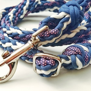 May include: Braided dog leash in shades of blue, white, and pink. The leash features a silver metal clasp and a matching square buckle. The rope is tightly woven, creating a durable and stylish accessory for pets.