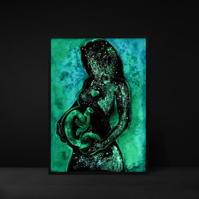 May include: A framed artwork depicting a pregnant person holding a fetus. The artwork is a silhouette in black with a green and blue background. The fetus and the person's silhouette glow with a green light, and the background has a watercolor effect.