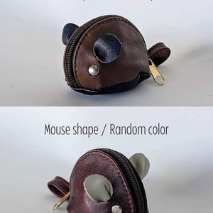 May include: A small brown leather coin purse shaped like a mouse. The purse has a zipper closure and a small, round, silver button on the side. The mouse's ears are made of black leather.