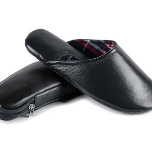 May include: A pair of dark blue leather slippers with a zippered pouch. The slippers have a plaid lining and are made of soft leather.