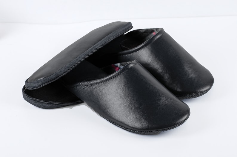 May include: A pair of black leather slippers with a zippered carrying case. The slippers have a soft, comfortable lining.