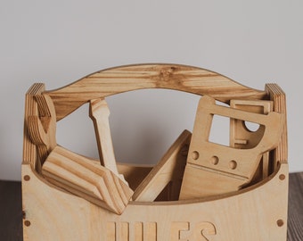 May include: A wooden toy toolbox with the name "JULES" engraved on the front. The toolbox is filled with various wooden tools, including a hammer, saw, and wrench.