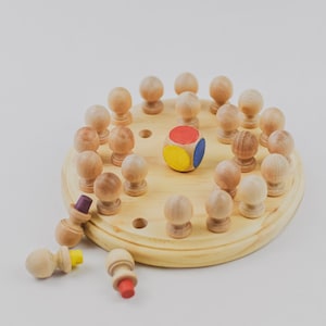 May include: A wooden game board with a circle of wooden pegs and a colorful die in the center. The die has red, yellow, and blue sections. Some pegs are missing from the board.