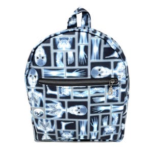 May include: A black backpack with a zippered pocket and a pattern of x-ray images of bones and skeletons.