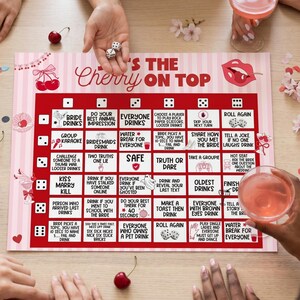 May include: A red and white board game with the text "'S THE Cherry ON TOP" and various game instructions. The game includes dice and is designed for a party or gathering. The game is surrounded by hands and drinks.