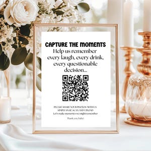May include: A framed sign with the text "CAPTURE THE MOMENTS" and a QR code. The sign also includes the text "Help us remember every laugh, every drink, every questionable decision..." and "PLEASE SHARE YOUR PHOTOS WITH US SIMPLY SNAP, SCAN AND UPLOAD".