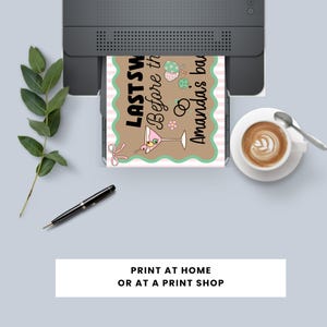 May include: A printed invitation card with the text "LAST SW Before the Amanda's bar" is emerging from a printer. The card has a brown background with a pink and white striped border and a martini glass illustration. A cup of coffee and a pen are also visible.