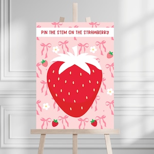 May include: A pink and white printable game board with the text "Pin the Stem on the Strawberry". The board features a large red strawberry with white seeds and a green stem. The background is pink with white bows and flowers.