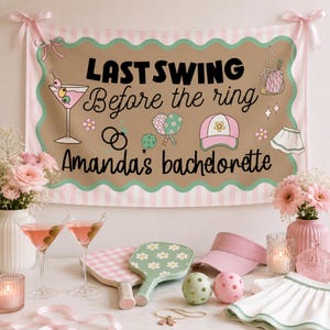 May include: A brown banner with the text "LAST SWING Before the ring Amanda's bachelorette" is displayed. The banner has a scalloped edge and pink and white stripes. Martini glasses, pickleball paddles, and a visor are on display.