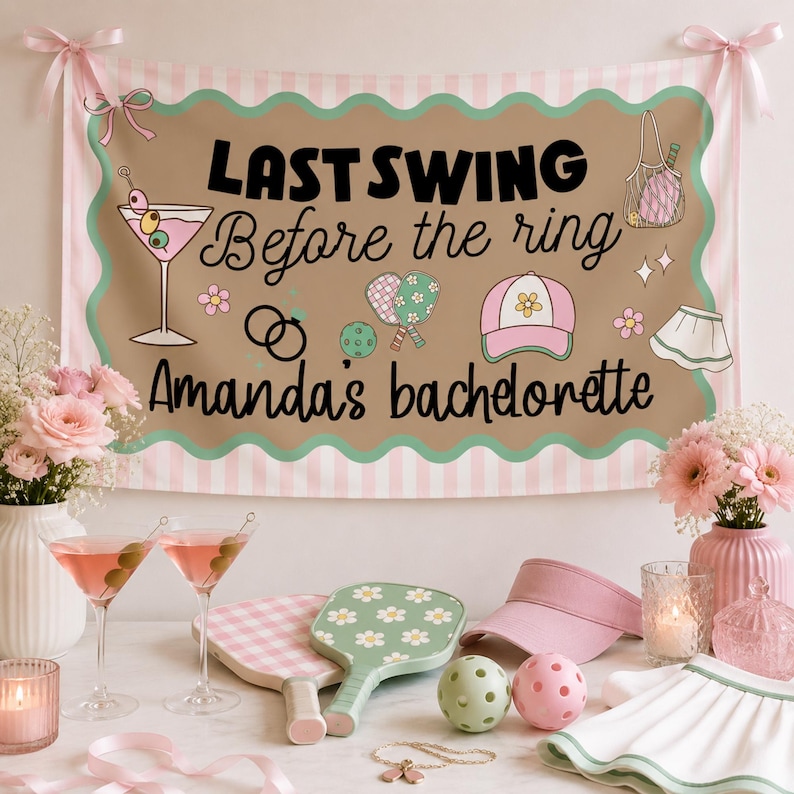 May include: A brown banner with the text "LAST SWING Before the ring Amanda's bachelorette" is displayed. The banner has a scalloped edge and pink and white stripes. Martini glasses, pickleball paddles, and a visor are on display.