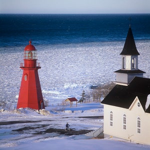 Lighthouse, the church of la Martre and a cyclist in winter, Gaspe Coast