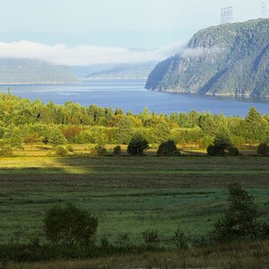 First light on a field at Sacré-Coeur and the Saguenay river and the fog