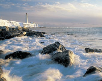 Foto afdrukken Eerste zonnestralen op de branding, rotsen en de oever van de vuurtoren van Cap-des-Rosiers in de winter, Gaspésie