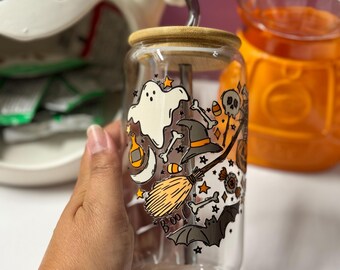 Peut inclure: Un gobelet réutilisable en verre transparent avec un couvercle en bambou et une paille en métal. Le gobelet est décoré d'un thème d'Halloween avec un fantôme, un chapeau de sorcière, un balai, une chauve-souris et le mot "BOO" imprimé dessus.