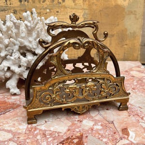 Soporte de escritorio doble de latón antiguo con detalles ornamentales y decoración de serpiente marina.