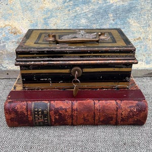 Antigua caja fuerte de metal japonesa de principios del siglo XX, con cerradura de latón de cuatro palancas y llave, asa de latón, bandeja extraíble para monedas y una hermosa pátina envejecida.