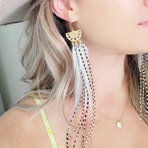 May include: Gold earrings with a crescent moon design and long white and black feathers.