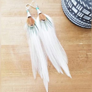 Pendientes de plumas blancas con detalles turquesa, estilo boho western.