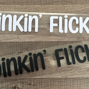 May include: Two vinyl decals, one white and one black, with the text "Dinkin' Flicka" in a playful, rounded font.