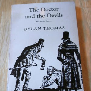 May include: A black and white illustration of a book cover with the title "The Doctor and the Devils" and the author "Dylan Thomas". The cover features three figures in black and white, two men in top hats and a man with a beard.