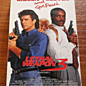 May include: VHS video cassette cover for the action film Lethal Weapon 3, featuring Mel Gibson, Danny Glover, and Joe Pesci. The cover features a red and white title card with the film's title, "Lethal Weapon 3", and a photo of the three actors holding guns.