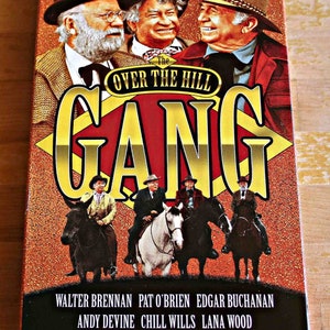May include: VHS box for "The Over the Hill Gang" featuring a cast of actors in cowboy hats and suits. The title is in large yellow letters with a red background. The bottom of the box lists the actors' names.