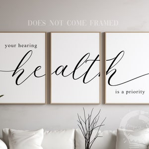 May include: Three framed prints with the text "your hearing health is a priority" in a modern calligraphy font. The prints are hung on a white wall.